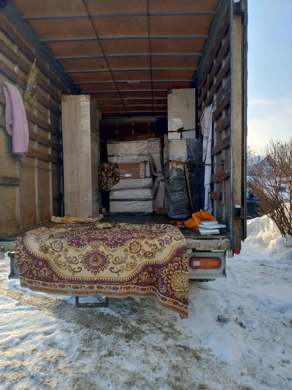 Ковёр и упакованная мебель в кузове на снегу